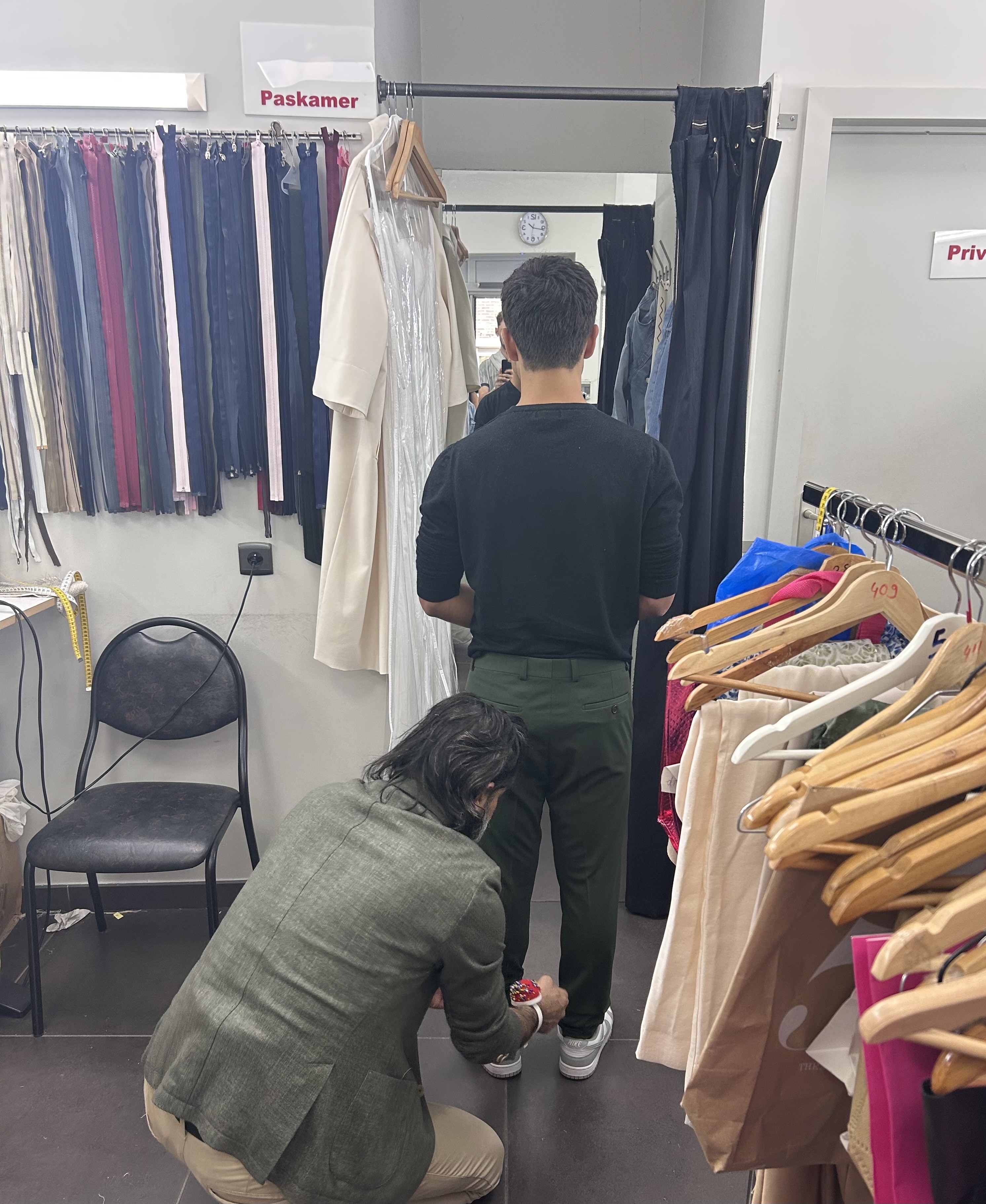 Kleermaker die de broek van een klant opmeet